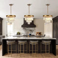 Load image into Gallery viewer, Three gold crystal chandeliers with black matte frame hanging above a marble kitchen island with gold bar stools