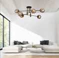 Load image into Gallery viewer, Modern living room with a white sectional sofa, black and gray cushions, wooden floor, and smoky glass globe chandelier