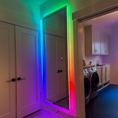 Load image into Gallery viewer, Tall rectangular wall-mounted mirror with adjustable multi-colored LED lighting in a modern laundry room setting