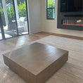 Load image into Gallery viewer, Minimalist square wooden coffee table with smooth brown finish on a neutral textured rug in modern living room
