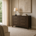 Load image into Gallery viewer, A dark brown wooden five-drawer dresser with gold bar handles in a styled bedroom setting, featuring a table lamp and books on top, with a neutral beige wall and framed art behind it.