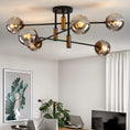 Load image into Gallery viewer, Modern ceiling chandelier with six smoke gray glass globes and matte black and gold metal frame in contemporary living room