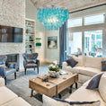 Load image into Gallery viewer, Capiz Shell Chandelier is over a coffee table in a living room that also has a sofa and chairs in it