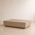 Load image into Gallery viewer, A modern rectangular beige coffee table with a light oak wood grain finish, shown in a minimalist room setting with a beige wall and tiled floor.