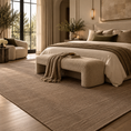 Load image into Gallery viewer, A large textured beige area rug in a modern, warm-toned bedroom setting. The rug covers the floor in front of and around a bed with neutral bedding, a matching upholstered bench, and a side chair near tall windows.