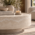 Load image into Gallery viewer, A round stone coffee table in a warm neutral beige tone, styled with stacked books, a ceramic vase of greenery, a candle, and a bowl in a softly lit living room.
