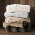 Load image into Gallery viewer, Luxury Faux Fur Throw folded and on top of a pile of other throw blankets on a shelf