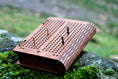 Load image into Gallery viewer, Compact wooden travel cribbage board with pegs displayed outdoors on moss-covered rock surface