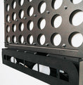Load image into Gallery viewer, Close-up of black metal life size wall-mounted Four in a Row game with round slots and disc storage tray on white background