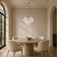 Load image into Gallery viewer, A luxury round crystal chandelier with a silver-toned metal frame hangs over a round wooden dining table and four upholstered cream chairs in a beautifully decorated beige dining room.