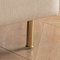 Load image into Gallery viewer, Close-up of a furniture leg in a gold color, attached to a beige upholstered MINIMALIST ACCENT CHAIR by House of Effy, standing on sturdy solid hardwood flooring with visible grain patterns.
