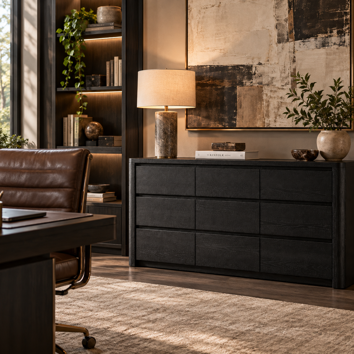 A dark charcoal wood 6-drawer dresser in a modern home office setting, styled with a table lamp, books, and a vase of greenery next to a leather office chair.