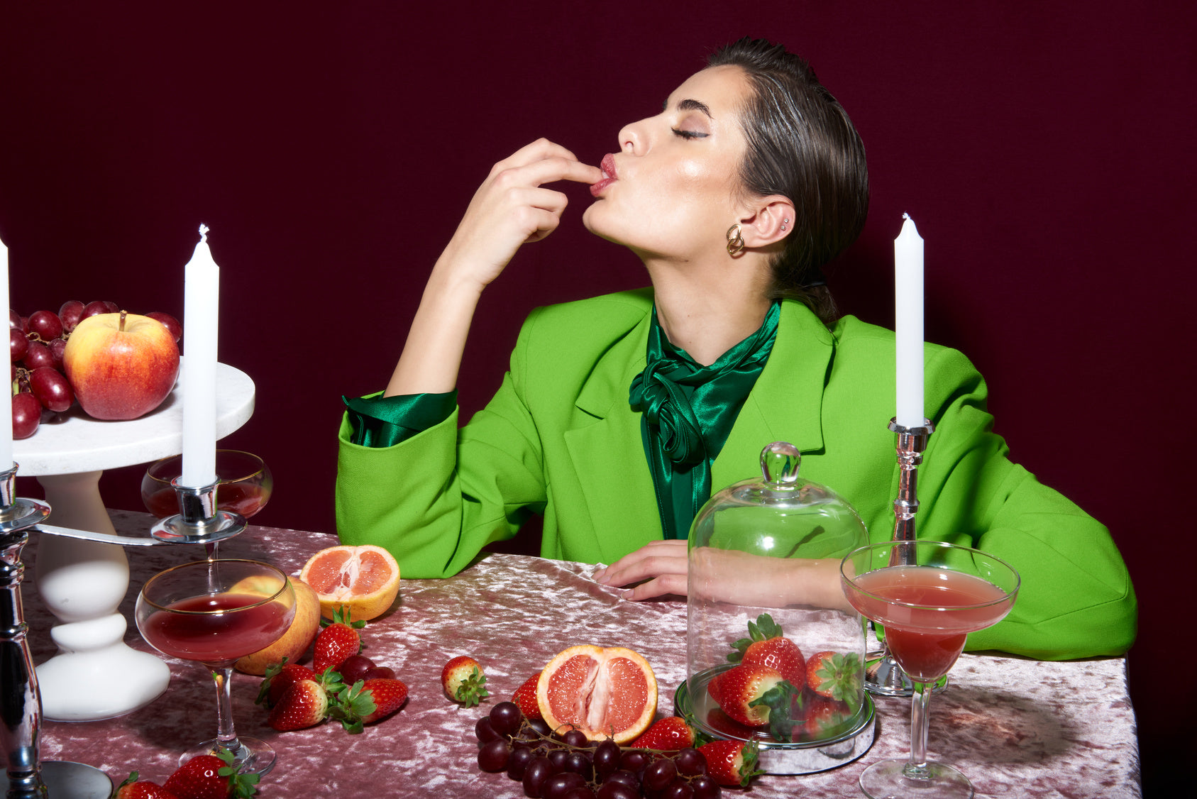woman licking fingers near table with fruit