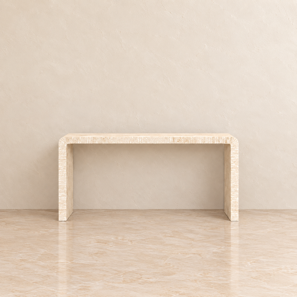 A minimalist console table with a curved top and thick blocky legs, crafted from a light beige textured stone or wood, set against a matching beige textured wall and floor.