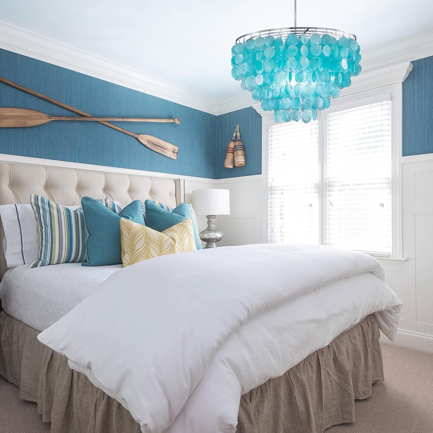 Capiz Shell Chandelier over a bed in a white and blue bedroom
