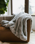 Load image into Gallery viewer, Soft gray Charlie Luxury Throw Blanket draped over brown leather sofa in cozy living room setting
