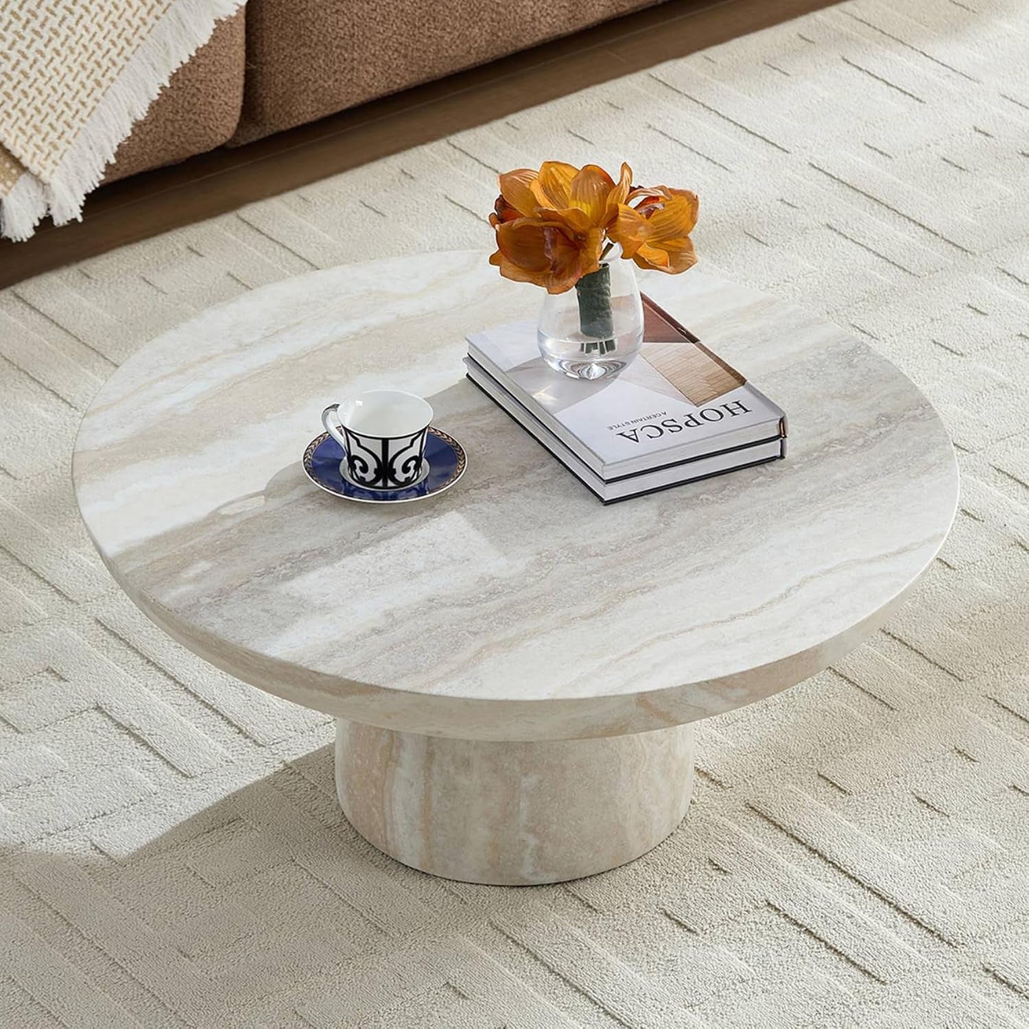 Cora Coffee Table is in a living room with a tea cup and books and vase with flowers sitting on it