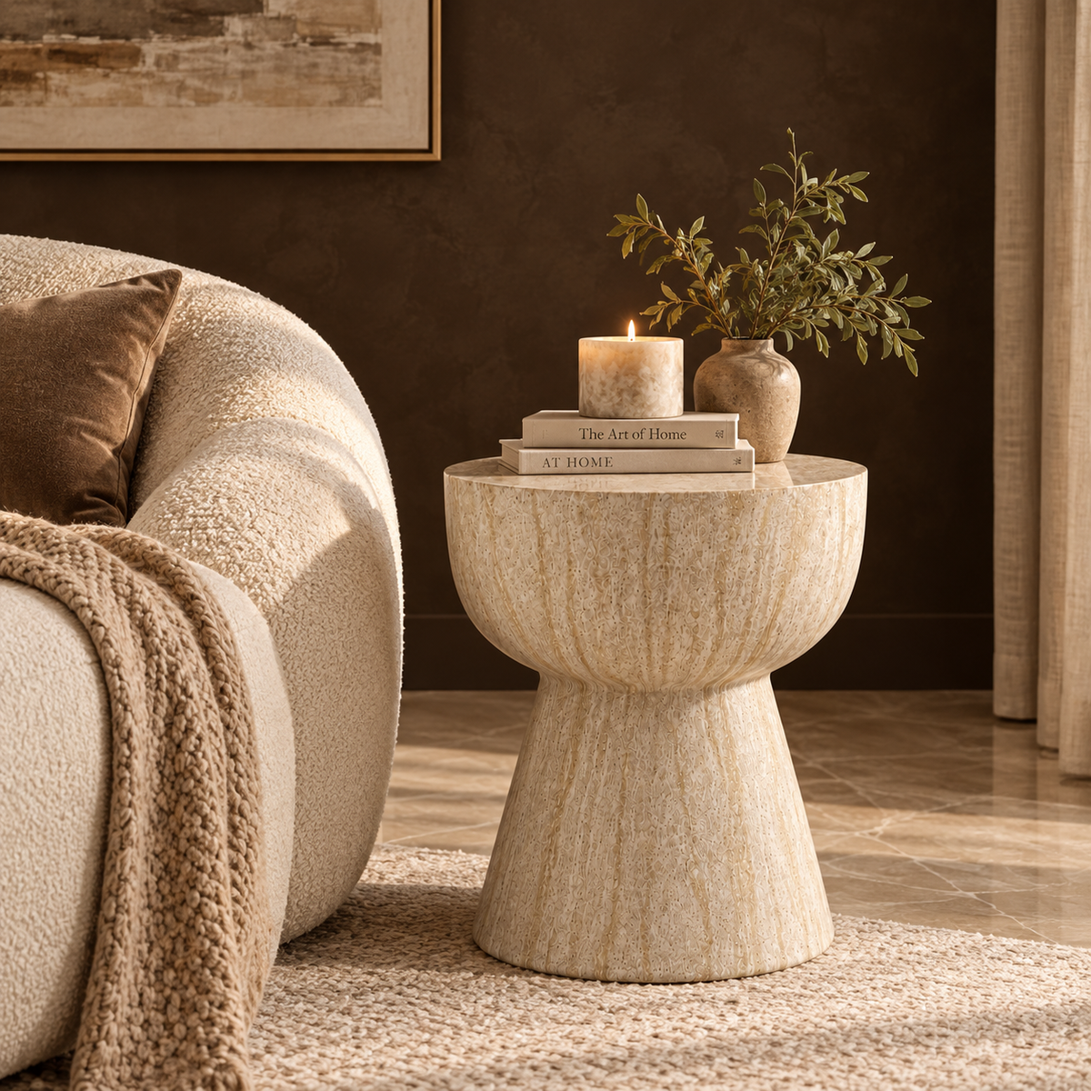 Ella round accent table with a beige stone-inspired finish beside a cream sofa in a modern