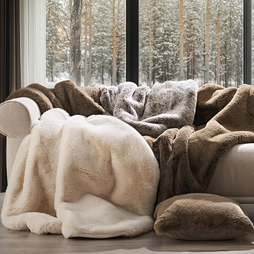 Faux Chinchilla Throw and other colors draped over a sofa in a living room next to a window
