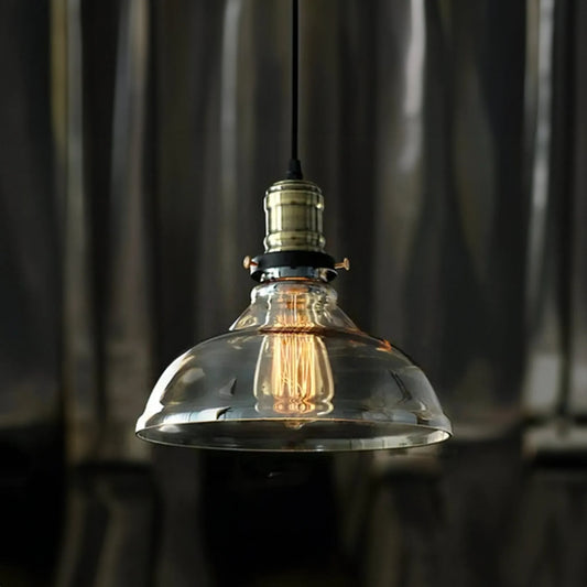 A vintage-style House of Effy gold pendant light with a clear glass shade and a visible filament bulb, hanging against a blurred metallic background.