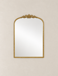 Load image into Gallery viewer, An ornate gold-framed wall mirror with a decorative crest at the top, shown against a textured beige wall.
