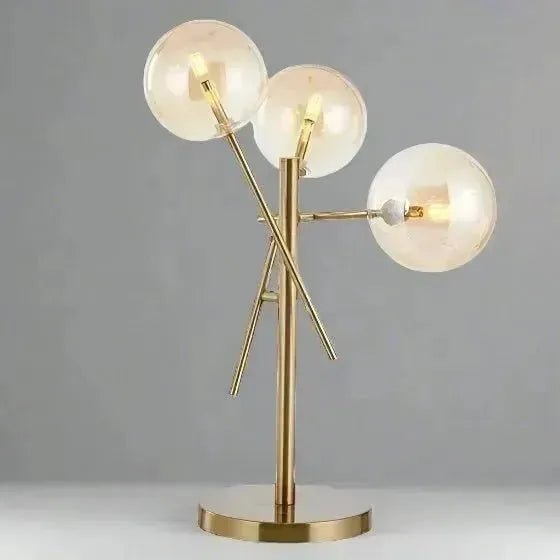 A luxury lighting masterpiece, the GLASS BALL TABLE LAMP by House of Effy features a sleek design with three spherical glass shades positioned at various angles on modern metal rods, set against a plain background.