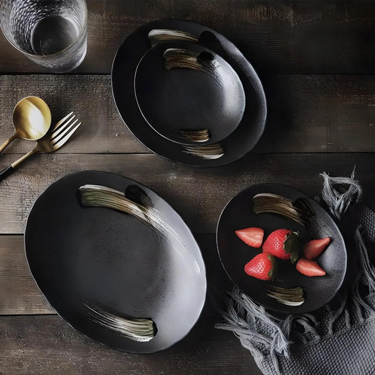 A luxurious dining experience featuring black dinnerware, including plates, bowls, and utensils. A MATTE BLACK CHARGER PLATE by House of Effy enhances the elegance, accompanied by a glass and three strawberries on a napkin.