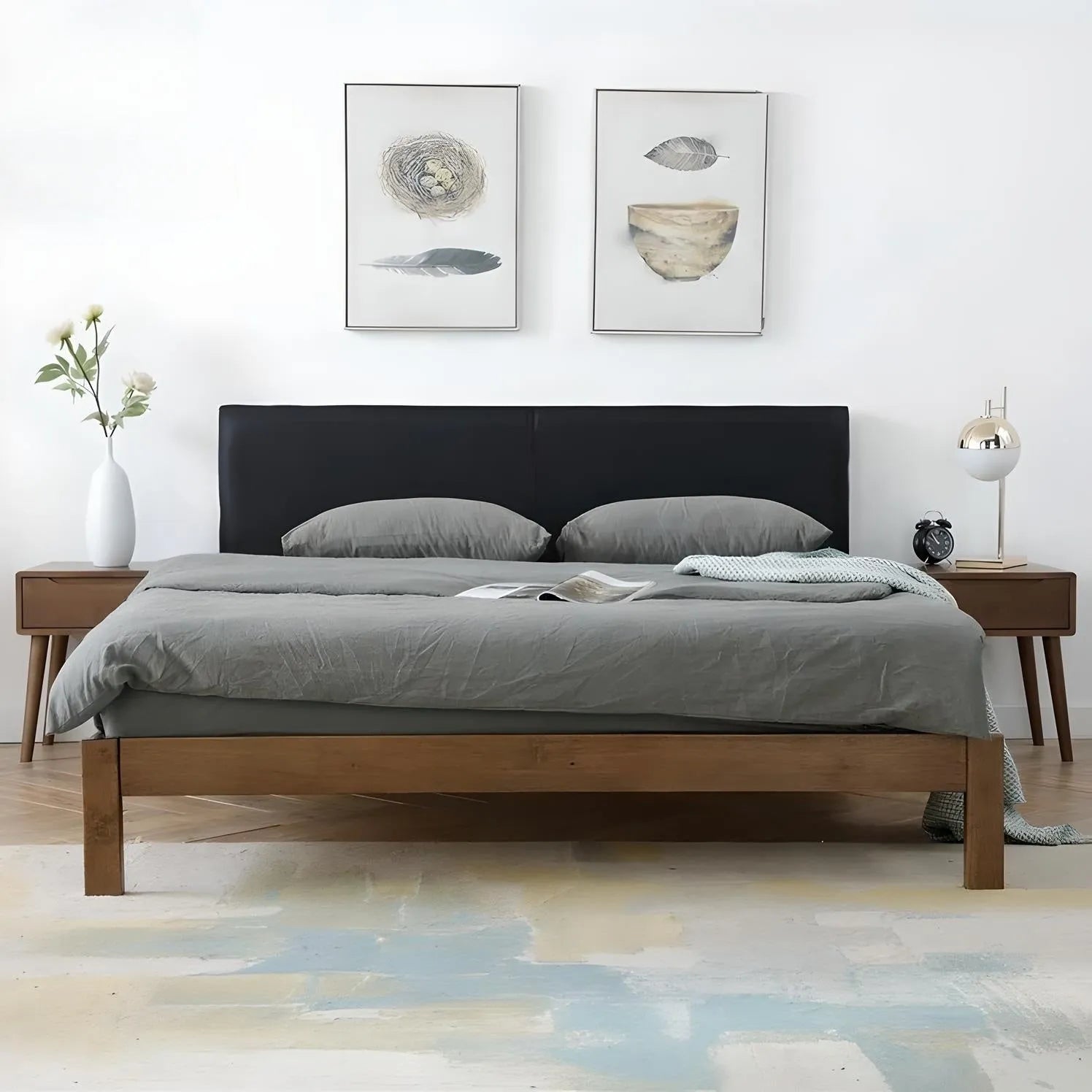 Bedroom with a luxurious House of Effy BROWN WOOD BED bed frame and dark grey bedding. Two nightstands with lamps flank the bed. Above the headboard are two abstract artwork pieces. A white and pastel rug is on the floor, enhancing the sophisticated atmosphere.