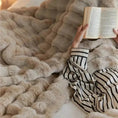 Load image into Gallery viewer, A person in striped pajamas is lying down under the winter warmth of a plush, beige TUSCAN THROW by House of Effy, holding and reading an open book.
