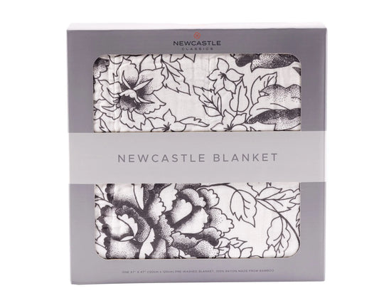 A packaged House of Effy ROSE BLANKET, featuring a luxurious black and white floral print, is labeled "Newcastle Blanket." The packaging showcases its size as 47 x 47 inches and highlights that the blanket is made from bamboo, perfect for adding a touch of elegance to your home décor.