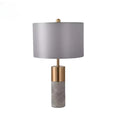 Load image into Gallery viewer, A House of Effy MODERN BEDSIDE LAMP with a cylindrical marble base, a gold metal connector, and a gray fabric drum shade, offering minimalistic design and ambient lighting.
