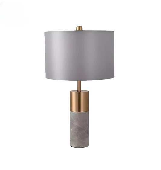 A House of Effy MODERN BEDSIDE LAMP with a cylindrical marble base, a gold metal connector, and a gray fabric drum shade, offering minimalistic design and ambient lighting.