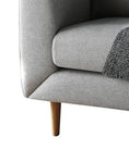 Load image into Gallery viewer, A close-up of a House of Effy MID-CENTURY MODERN LOVESEAT SOFA's corner, showcasing its Mid-Century Modern wooden leg and a grey knitted blanket draped over the seat cushion.
