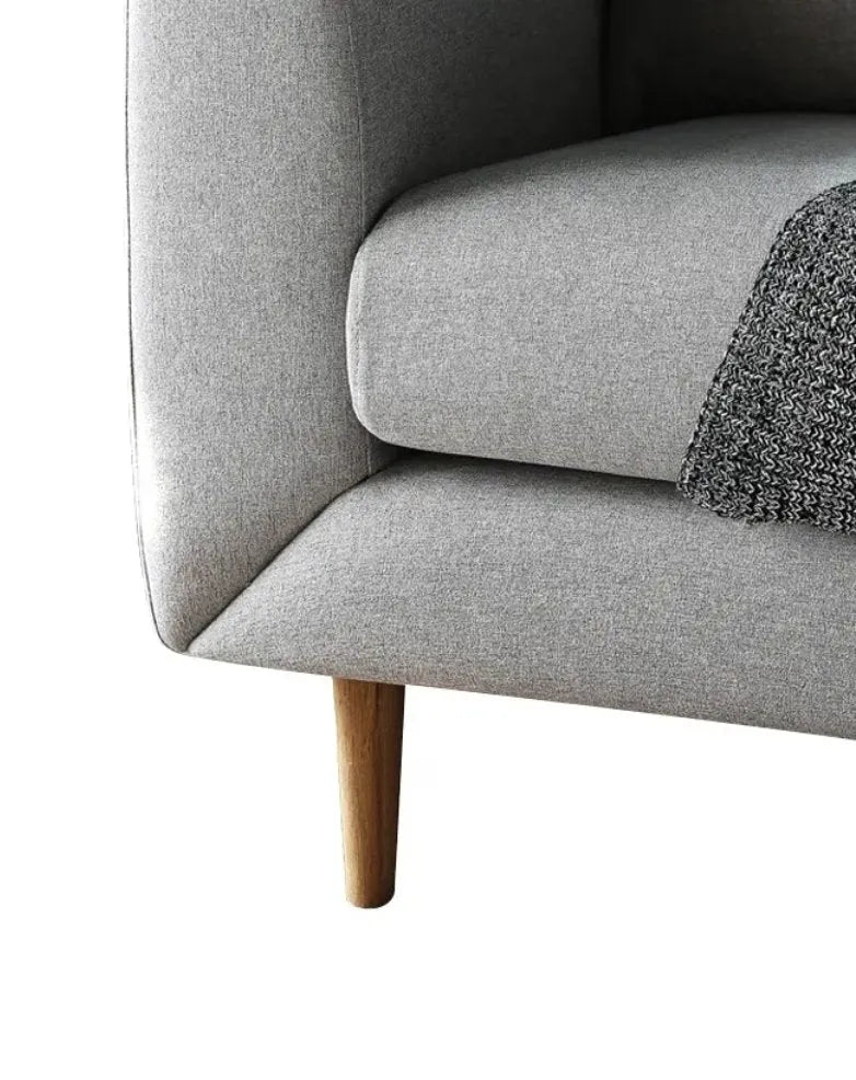 A close-up of a House of Effy MID-CENTURY MODERN LOVESEAT SOFA's corner, showcasing its Mid-Century Modern wooden leg and a grey knitted blanket draped over the seat cushion.