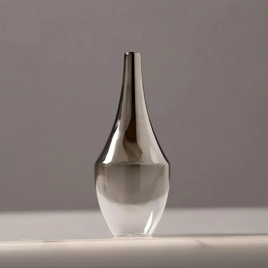 A sleek, transparent MODERN MINIMALIST VASE from House of Effy with a narrow neck and bulbous base, displayed against a soft gray background, is perfect for modern minimalist floral arrangements.