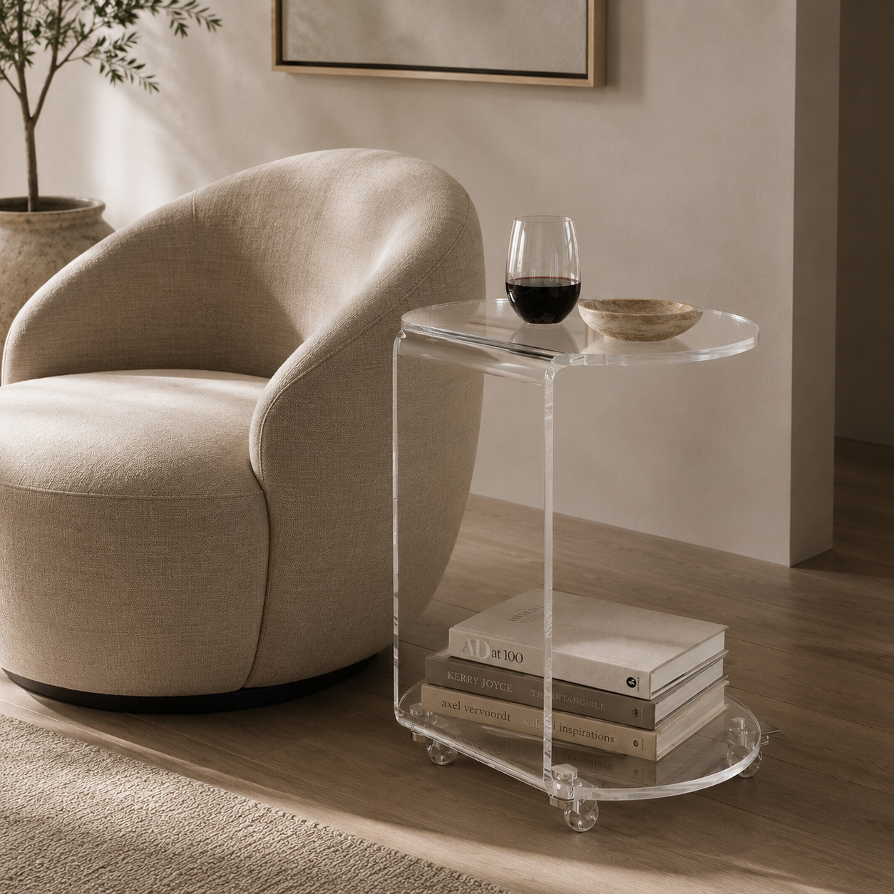 A modern acrylic side table with clear glass wheels and a rounded top, styled next to a beige armchair in a minimalist living room setting.