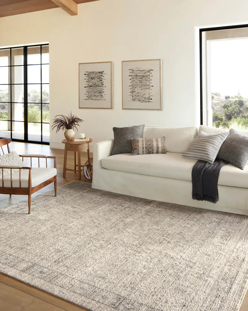 area rug with sofa and chair next to a window with pillows on it