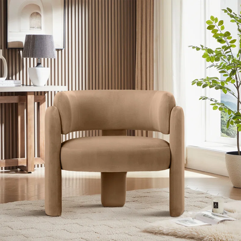 barrel chair in living space next to faux plant and a window on top of an area rug