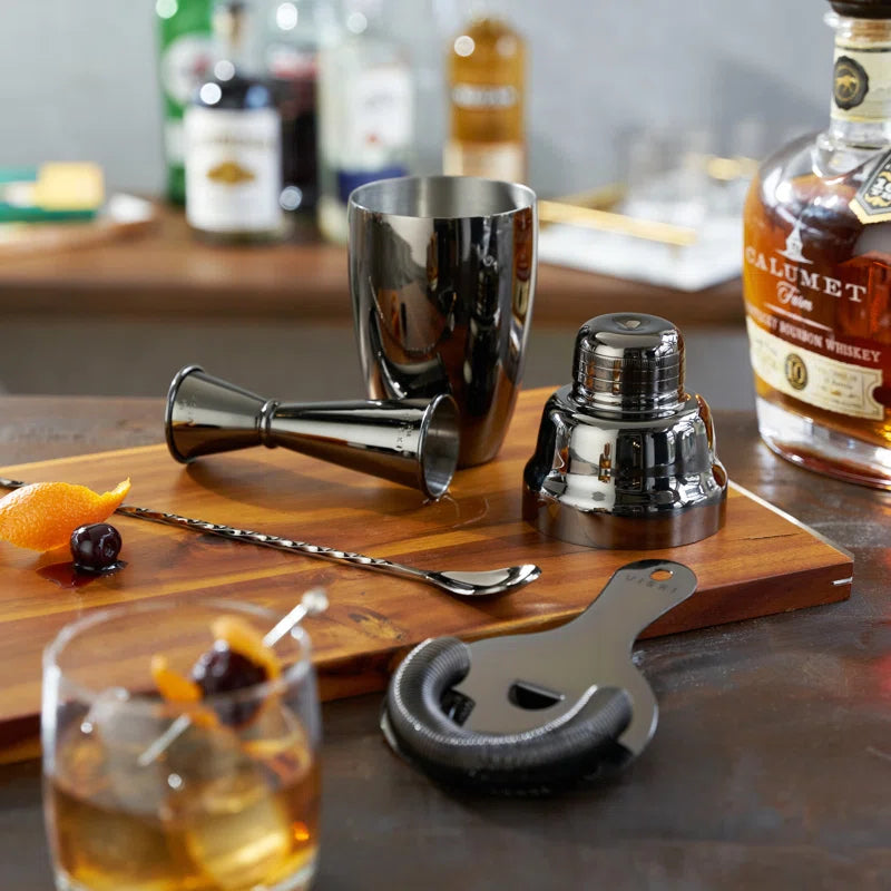 barware set on table and cutting board next to whiskey and a made cocktail