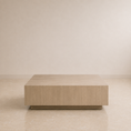Load image into Gallery viewer, A low, rectangular coffee table with a light oak wood grain finish, positioned against a minimalist beige wall and tiled floor.
