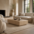 Load image into Gallery viewer, A modern living room featuring a light beige sectional sofa, a matching low wooden beige coffee table, a textured beige rug, and a minimalist black fireplace in the background.
