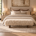Load image into Gallery viewer, A styled bedroom scene featuring a bed dressed in cream and taupe bedding, a shaggy cream bench at the foot, matching pillows, bedside tables with lamps, and a large abstract painting above the headboard.
