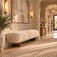 Load image into Gallery viewer, A long bench upholstered in fluffy cream sheepskin sits in a warm, modern entryway with wood floors, a large textured wall art piece, wall sconces, and a woven rug.
