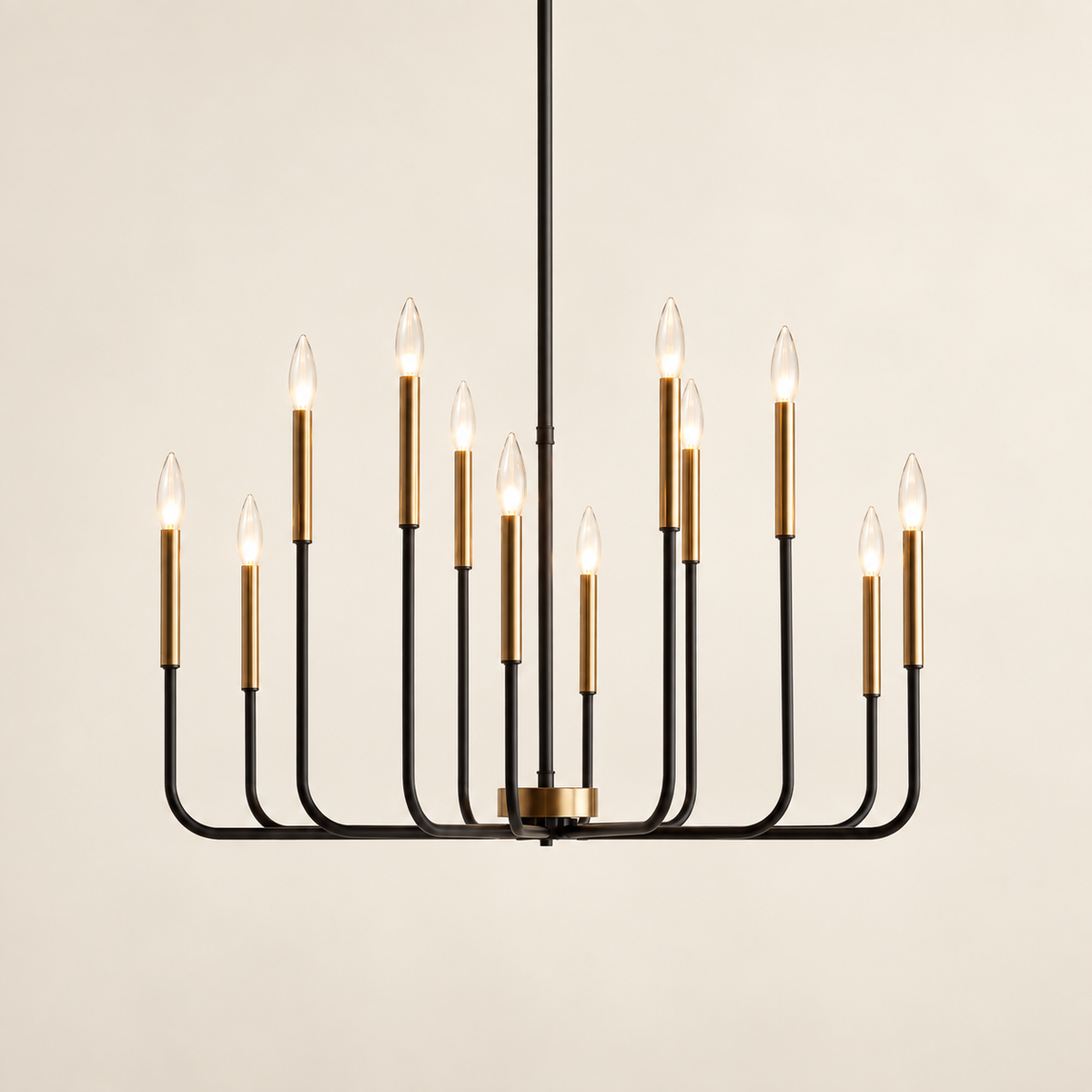 A modern 12-light chandelier with a matte black metal frame and brushed brass cylindrical candle-style bulbs, suspended against a warm off-white background.