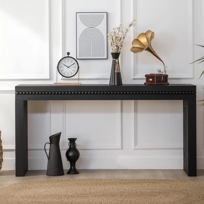black console table in decorated room with a vase and clock on it