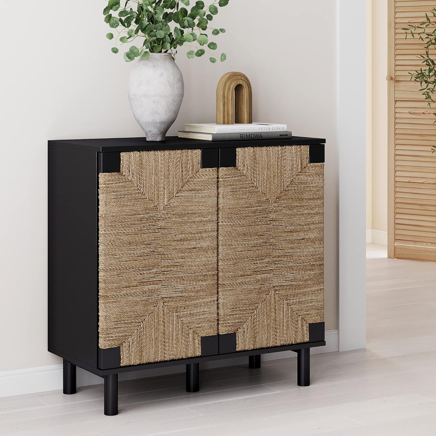 black credenza in a room with a vase and books on it on top of hardwood floor