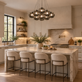 Load image into Gallery viewer, Black globe chandelier with smoked gray glass shades hanging above a marble kitchen island in a luxury kitchen with cream cabinetry.
