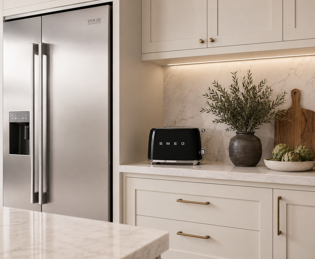 A black SMEG toaster sits on a light marble countertop in a modern kitchen setting next to a stainless steel refrigerator.