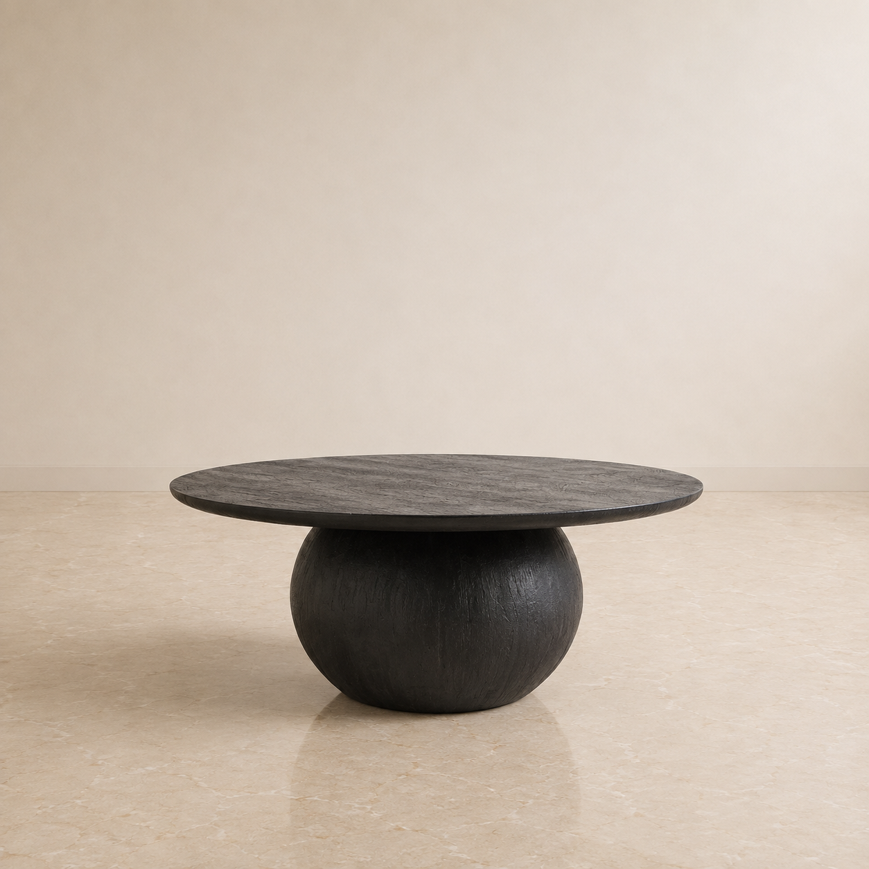 A round black stone coffee table with a textured top and a rounded pedestal base, set against a minimalist beige wall and floor.