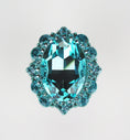 Load image into Gallery viewer, Close-up of an oval turquoise crystal cabinet knob with smaller round crystals in a polished silver setting on white background
